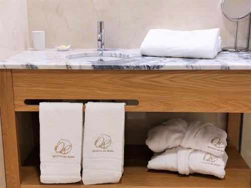 a bathroom with a sink and towels under a counter at Quinta da Roda Hotel - Conforto e Tranquilidade no Gerês in Cela