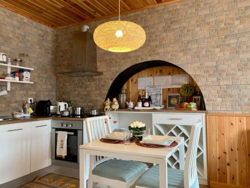 a kitchen with a table in a kitchen with a brick wall at Casa do Priolo - Villaverde Azores in Feteiras