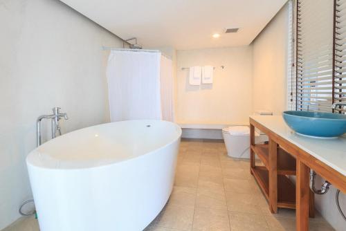 a bathroom with a large tub and a sink at De Pastel Hua Hin in Hua Hin