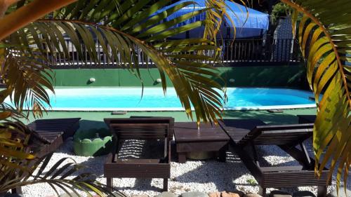 a table and chairs next to a swimming pool at Hotel Bela Onda in Bombinhas