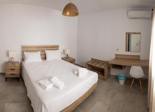 a bedroom with a large white bed and a desk at Nissea Apartments in Naxos Chora