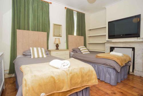 1 dormitorio con 2 camas y TV de pantalla plana en pedro host family en Londres