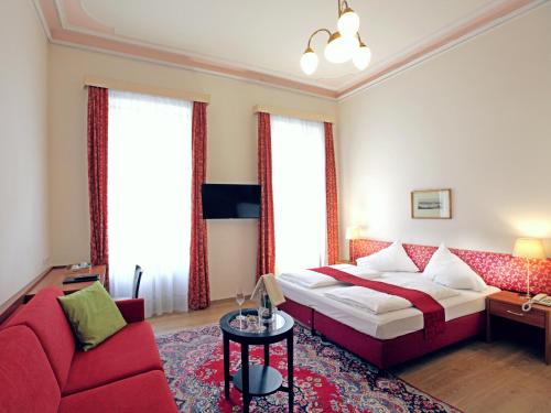 Una habitación de hotel con una cama y un sofá rojo. en HPA Hotel Andreas, en Viena
