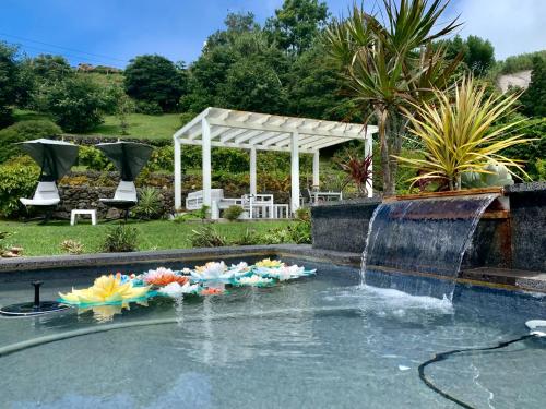 a pool with a bunch of flowers in the water at Casa do Milhafre - Villaverde Azores in Feteiras