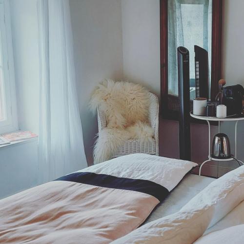 a bedroom with a white chair with a furry pillow at La Loge du Grand Cèdre, chambre d'hôtes SoCosy in Fontcouverte