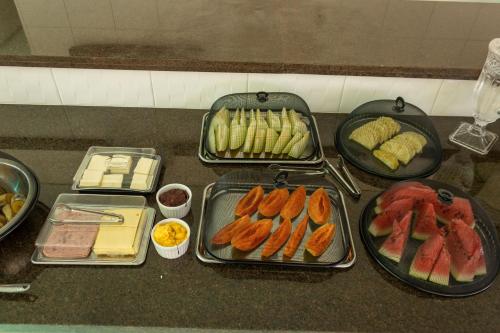 a table with trays of different types of food at Paraiso Barra Hotel in Barra de Santo Antônio