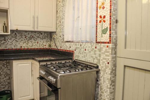 a kitchen with a stove and a tiled wall at Semeni Asante Guesthouse in Johannesburg