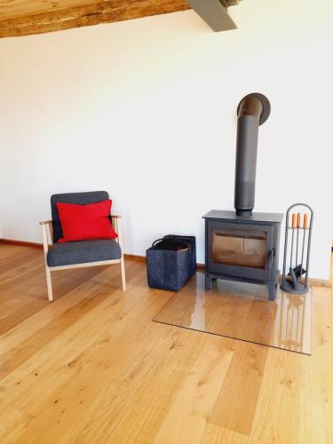 a living room with a wood stove and a chair at Hof Ruemland Ferienwohnungen in Hollingstedt