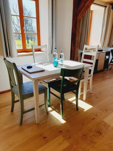 a white table with chairs and bottles on it at Hof Ruemland Ferienwohnungen in Hollingstedt