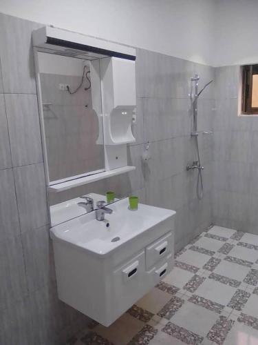 a white bathroom with a sink and a mirror at HEBERTOGO Casablanca in Lomé