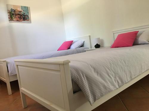 1 dormitorio con 2 camas y almohadas rojas y blancas en Les oliviers de Murateddu (Maison individuelle), en Porto Vecchio