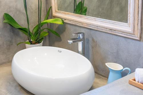 a white sink in a bathroom with a plant at CORFOS BLUE MYKONOS in Ornos
