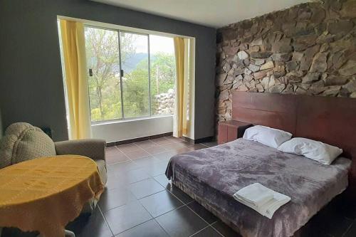 een slaapkamer met een bed en een stenen muur bij Residencia en Tomatitas in Tarija