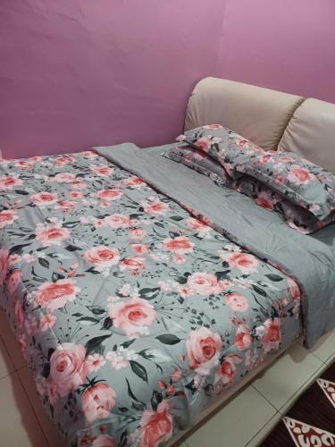 a bed with a floral comforter on it at Homestay Dalia, Beseri, Perlis in Kangar