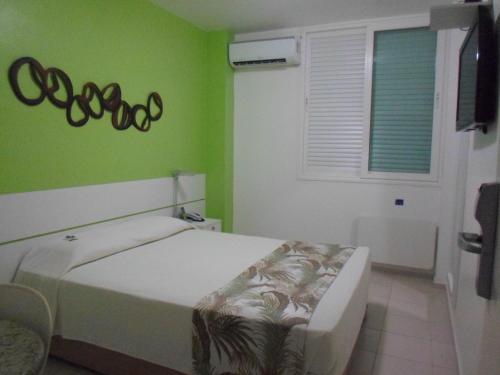 a bedroom with a bed and a green wall at Coqueiros Express Hotel in Maceió