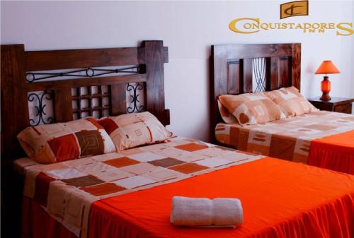 a bedroom with two beds with orange sheets at Hotel Conquistadores Inn in Ica