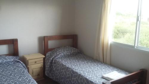 two beds in a small room with a window at Ecos de Montaña Cabañas in Cafayate