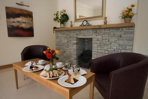 a table with plates of food and a fireplace at Deebert House Hotel in Kilmallock