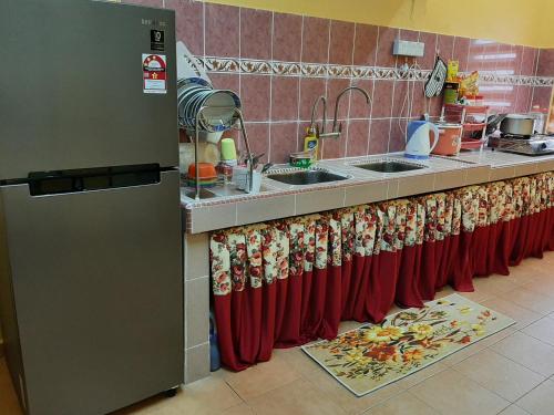 a kitchen counter with red curtains and a sink at HAIDA'S HOMESTAY Seri Iskandar, Perak in Seri Iskandar