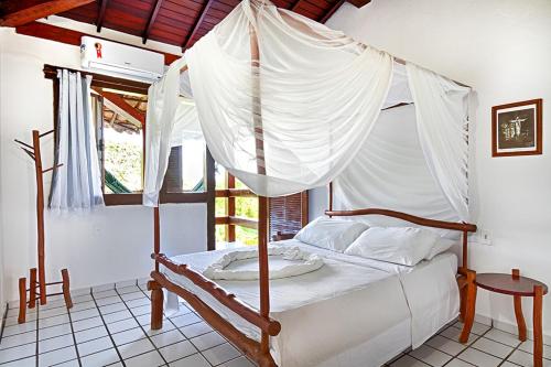 a bedroom with a canopy bed with white curtains at Novos Baianos Hostel e Pousada in Arraial d'Ajuda