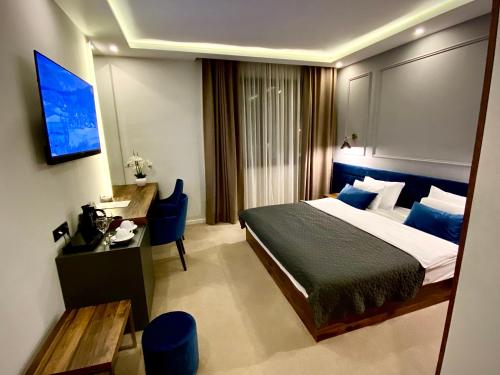 Schlafzimmer mit einem Bett, einem Schreibtisch und einem TV in der Unterkunft IG Hotel in Gornji Milanovac