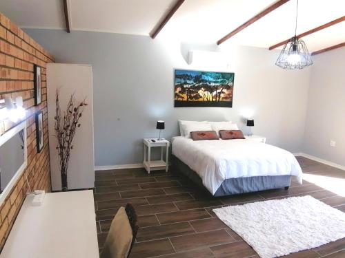 a bedroom with a white bed and a table at Thatchers Guest Rooms in Welkom