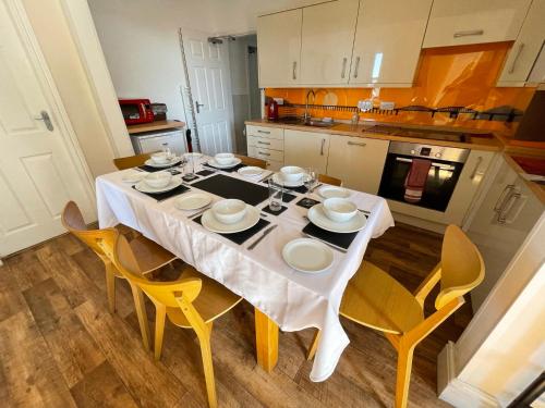 a kitchen with a dining table with yellow chairs at Hawen - Barmouth in Barmouth