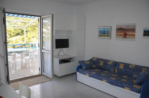 sala de estar con sofá azul y TV en Ponza Holiday Homes - Cala Feola, en Ponza