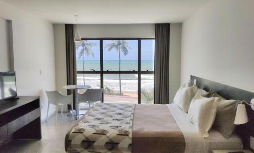 um quarto com uma cama e vista para a praia em Flat Frente Mar + Limpeza | R206 em Maceió