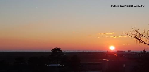 una puesta de sol sobre el océano con el sol en el cielo en Hotel Seeburg, en Sankt Peter-Ording