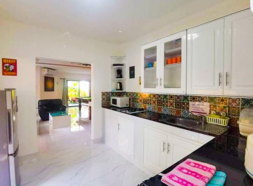 a kitchen with white cabinets and a black counter top at CORNER VILLA - PATTAYA HOLIDAY HOUSE WALKING STREET 4 bedrooms in Pattaya South