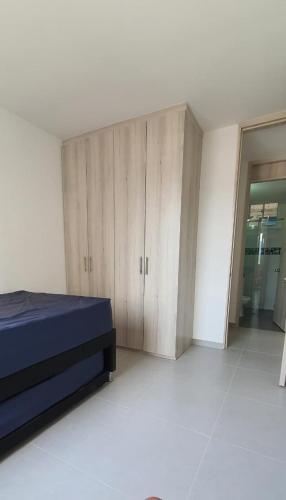 a bedroom with a bed and wooden cabinets at Hermoso apartamento en Reserva del peñon in Girardot