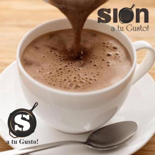 a cup of coffee on a plate with a spoon at Hotel Restaurante Sion in Moniquirá