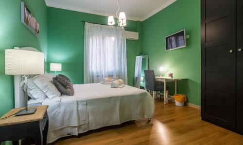 - une chambre avec des murs verts, un lit et un bureau dans l'établissement LE STANZE DI LUCA, à Palerme