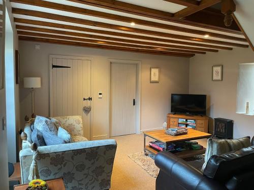 ein Wohnzimmer mit einem Sofa und einem TV in der Unterkunft Farriers Cottage in Grantham