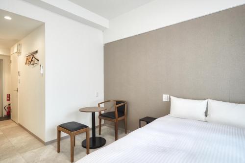 a bedroom with a bed and a small table at BiBi Hotel Naminoue in Naha