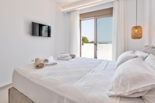 a white bedroom with a large bed with towels on it at Villa Lara AmberBlue Pefkos in Pefki