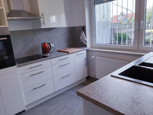 Una cocina con gabinetes blancos y una ventana. en Traumwohnung in Feldrandlage, en Rod am Berg