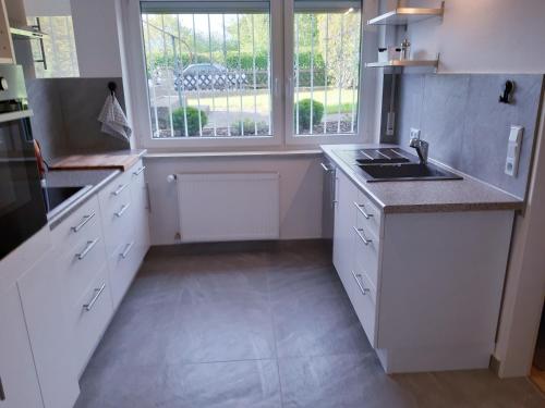 eine weiße Küche mit Spüle und Fenster in der Unterkunft Traumwohnung in Feldrandlage in Rod am Berg