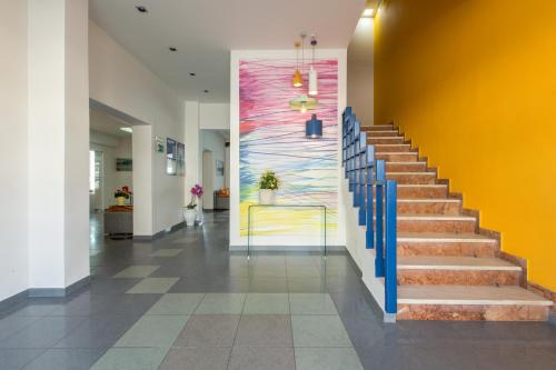 a lobby with stairs and a colorful wall at Flisvos Hotel in Tolo