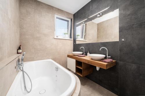 a bathroom with two sinks and a bath tub at Slnečný dom pri jazere in Hrubá Borša