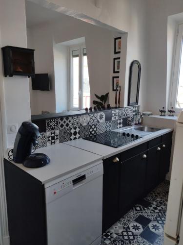 una cocina con azulejos blancos y negros en las encimeras en Appartement pied de plage, en San Juan de Luz