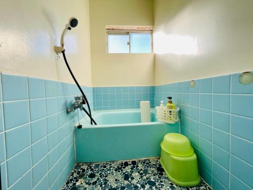 a blue bathroom with a tub and a green stool at 皆様お宿　海風 in Hiki