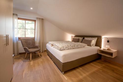 a bedroom with a bed and a chair and a window at Apartments Wolkan in Appiano sulla Strada del Vino