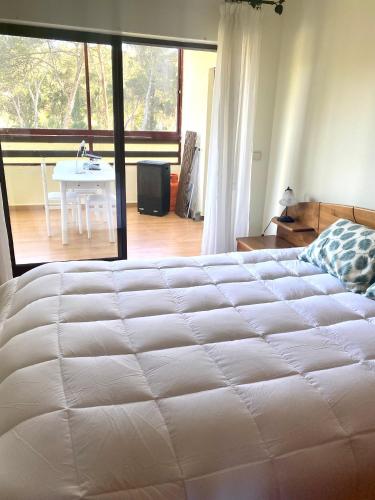 a bedroom with a large white bed and a table at Plage João de Caparica in Costa da Caparica