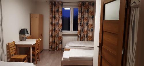 a room with two beds and a desk and a window at Noclegi nad Biebrzą Stara Szkoła in Wroceń