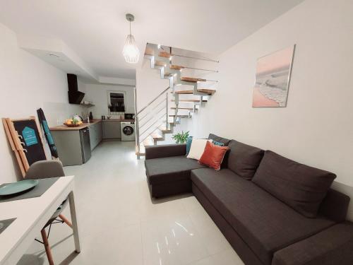 a living room with a couch and a staircase at Domki Apartamentowe ITALIA in Karwia