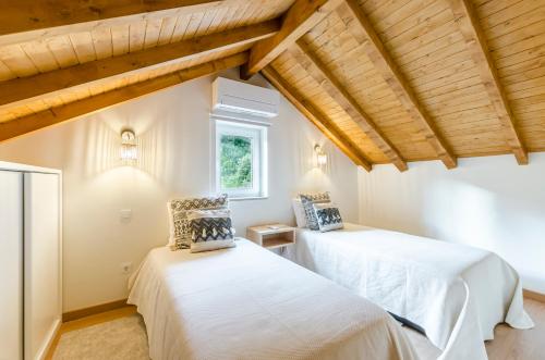 two beds in a room with wooden ceilings at Chalet Villas Gerês in Geres