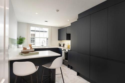 uma cozinha com cadeiras brancas e armários pretos em Period Henley 2 bed apt with parking for 1 car em Henley on Thames