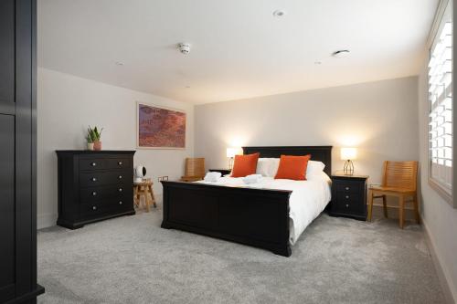 um quarto com uma cama grande e almofadas laranja em Period Henley 2 bed apt with parking for 1 car em Henley on Thames